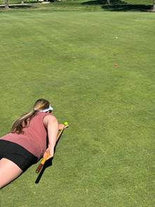 A person lying on the ground with a golf club and a ball

AI-generated content may be incorrect.